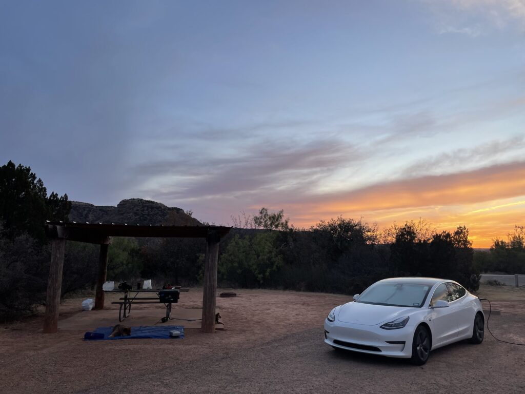 Tesla Model 3 parket ved en campingplads ved solnedgang