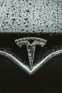 Teslas logo dækket af regndråber på en bil.