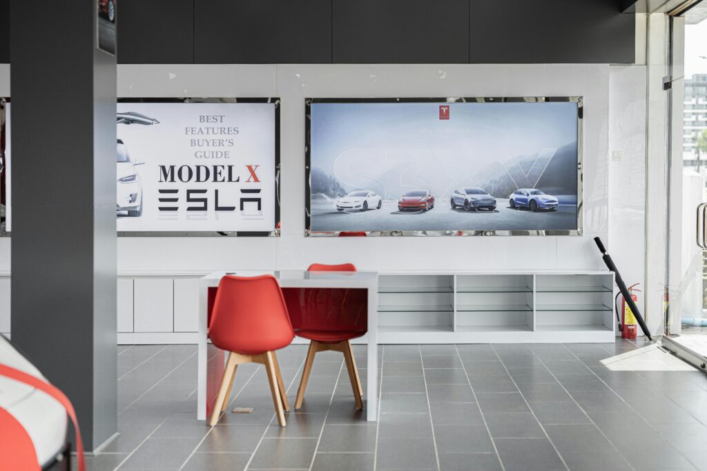 Tesla biludstilling med Model X plakat og fire biler i baggrunden