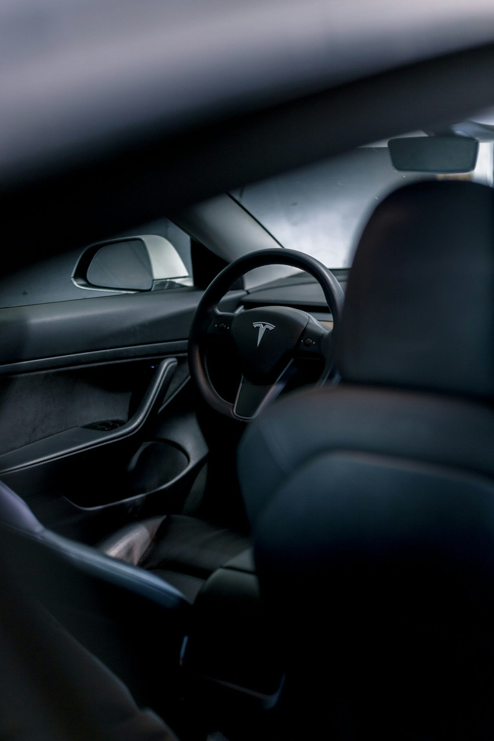 Tesla bilinteriør med synlig Tesla-logoen på rattet set fra førersædet