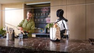 En mand står ved siden af en humanoid robot i et moderne køkken, klar til at lave mad med smarte køkkenredskaber.