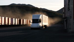 Tesla Semi lastbil kører ned ad en vej i et øde landskab ved solnedgang