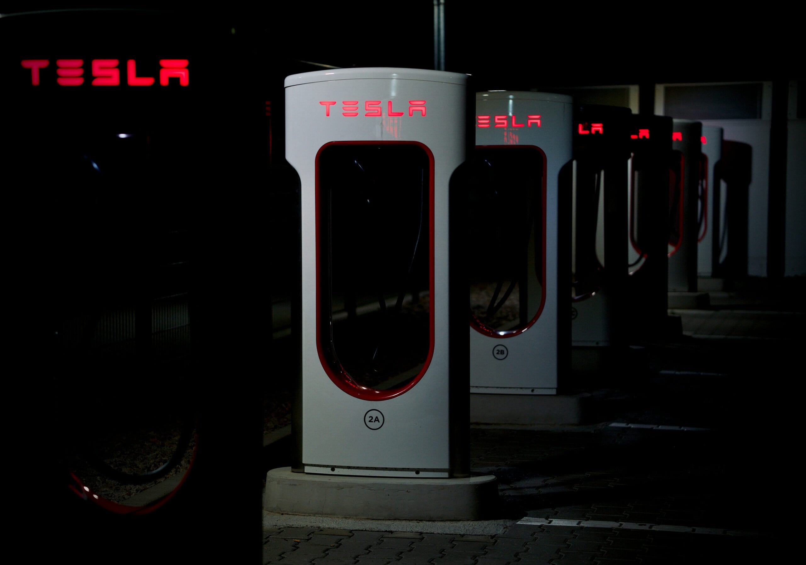 Tesla Supercharger-station oplyst om natten med flere opladningspunkter på række.