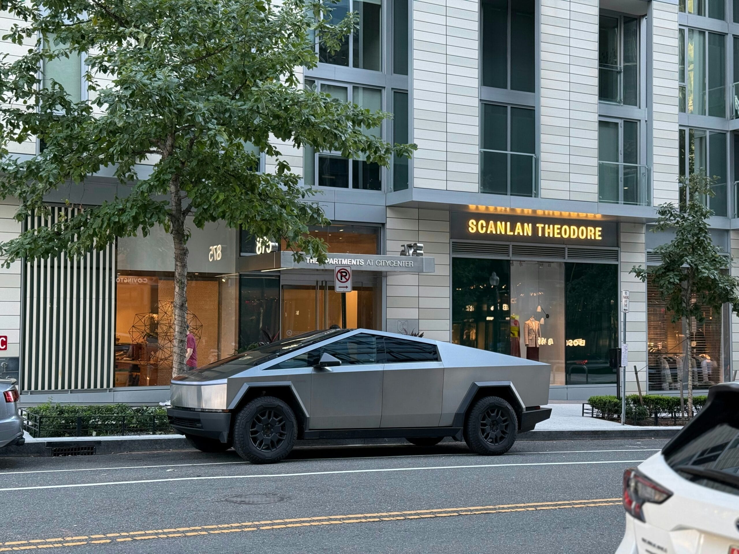 Tesla Cybertruck parkeret foran en moderne bygning med Scanlan Theodore-butikken i baggrunden.