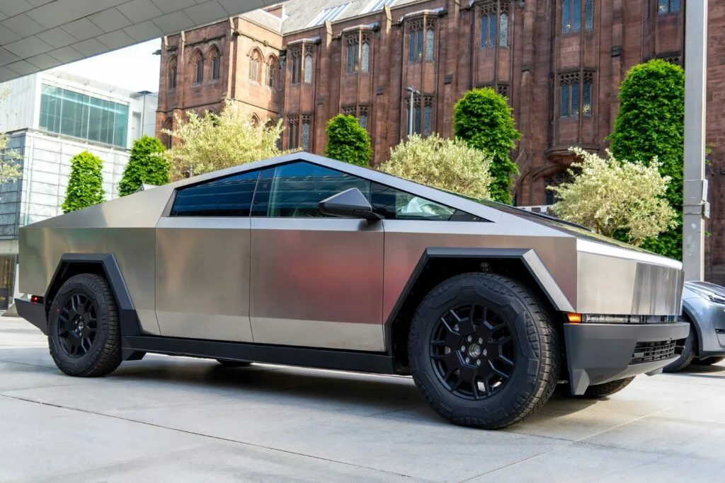 Tesla Cybertruck parkeret foran en historisk bygning med moderne og unikke designlinjer.