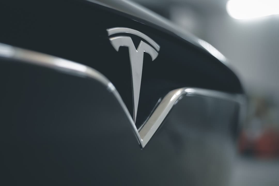 Nærbillede af Tesla-logo på fronten af en sort bil i en oplyst garage