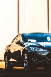 Sort Tesla elbil set forfra i solnedgangen, med refleksioner på dens glatte karrosseri.