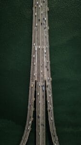 Luftfoto af en bred motorvejsbro med køretøjer, omgivet af grønt vand, der illustrerer moderne infrastruktur og transport.