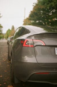 Bagenden af en sort Tesla elbil parkeret på en naturskøn vej