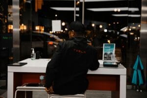 Person i Tesla-jakke sidder ved et bord i en moderne butik