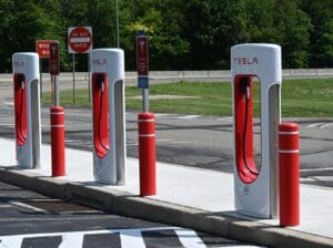 Fire Tesla ladestandere på en parkeringsplads med grønt område i baggrunden