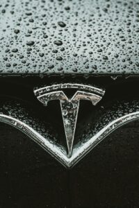 Tesla logo dækket af regndråber på bilens overflade