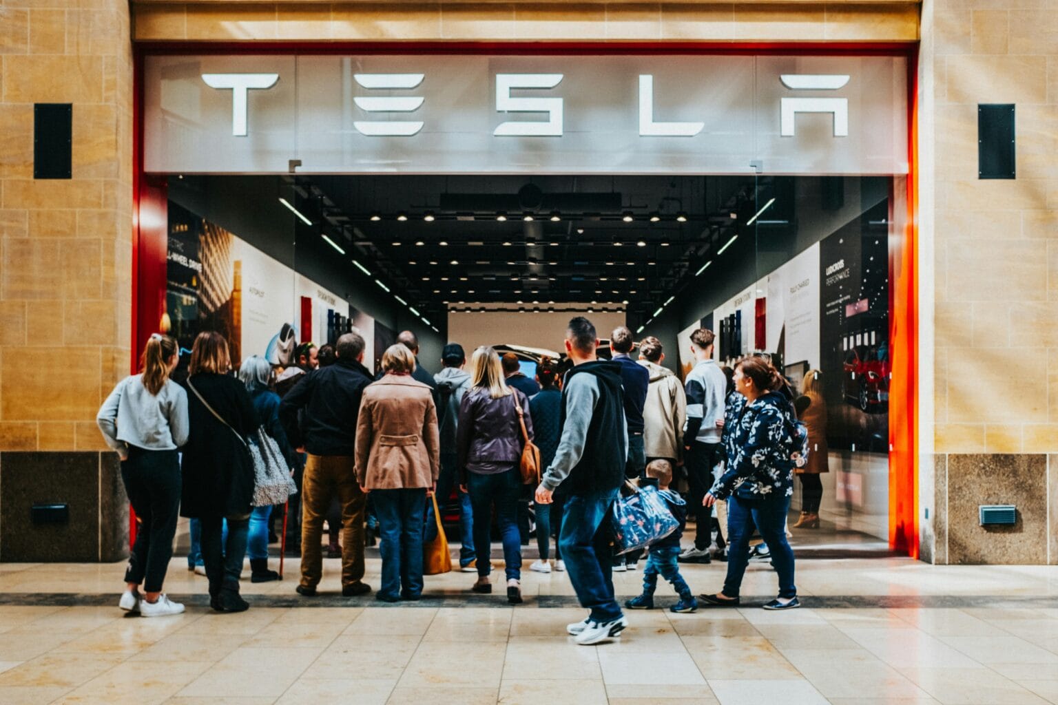 En gruppe mennesker går ind i en Tesla butik i et indkøbscenter.