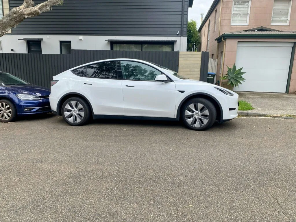 Hvid Tesla Model Y parkeret foran et hus i et boligområde