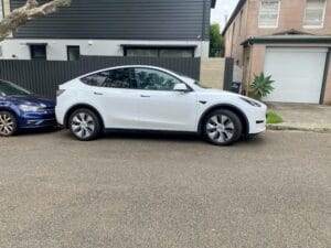 Hvid Tesla Model Y parkeret foran et hus i et boligområde