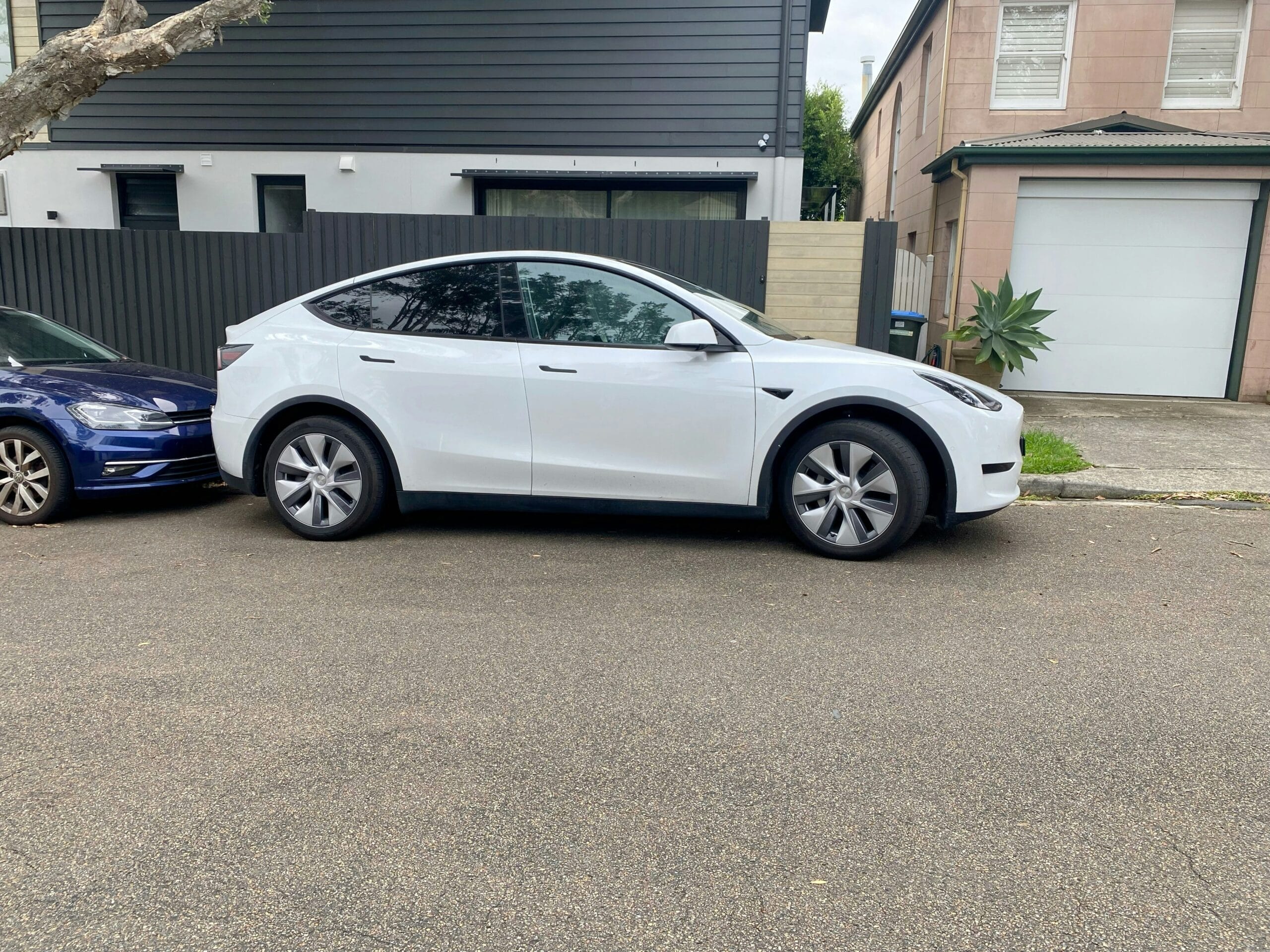 Hvid Tesla Model Y parkeret foran et hus i et boligområde