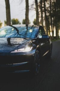 Tesla elbil kører på landevej omgivet af skov