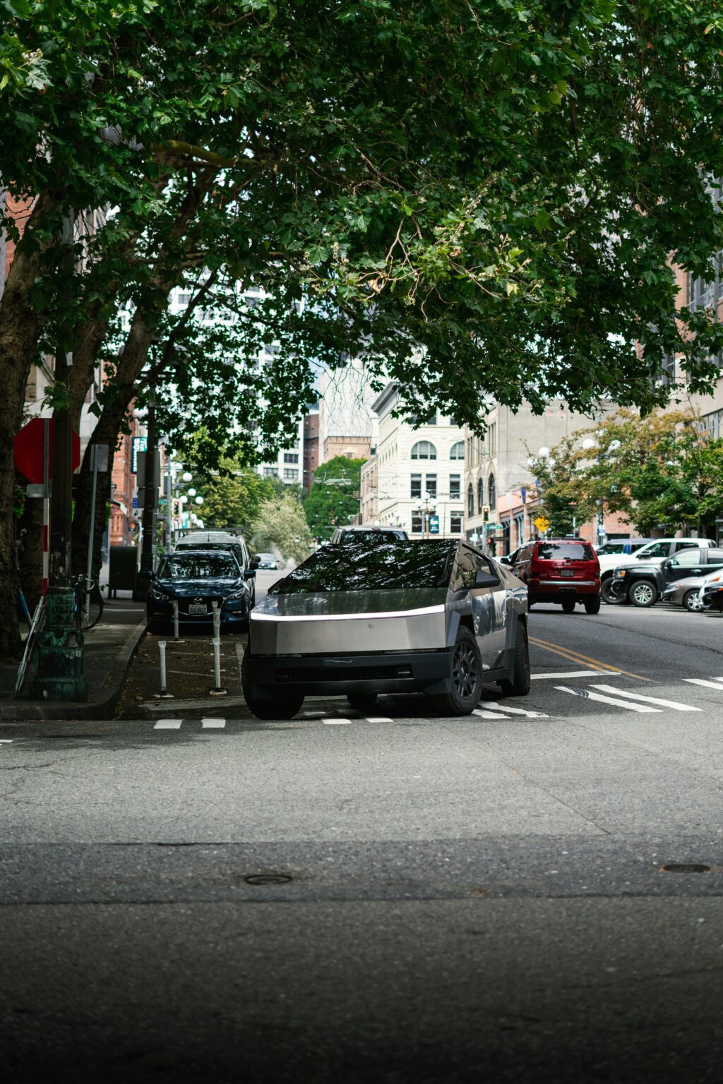 Tesla Cybertruck parkeret under træer i en by.