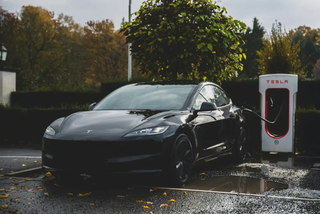 Sort Tesla oplader ved en Tesla Supercharger station i efterårslandskab