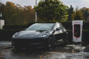Sort Tesla oplader ved en Tesla Supercharger station i efterårslandskab