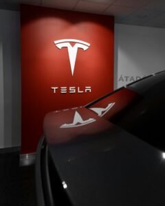 Tesla logo på rød væg ved siden af bilrefleksion