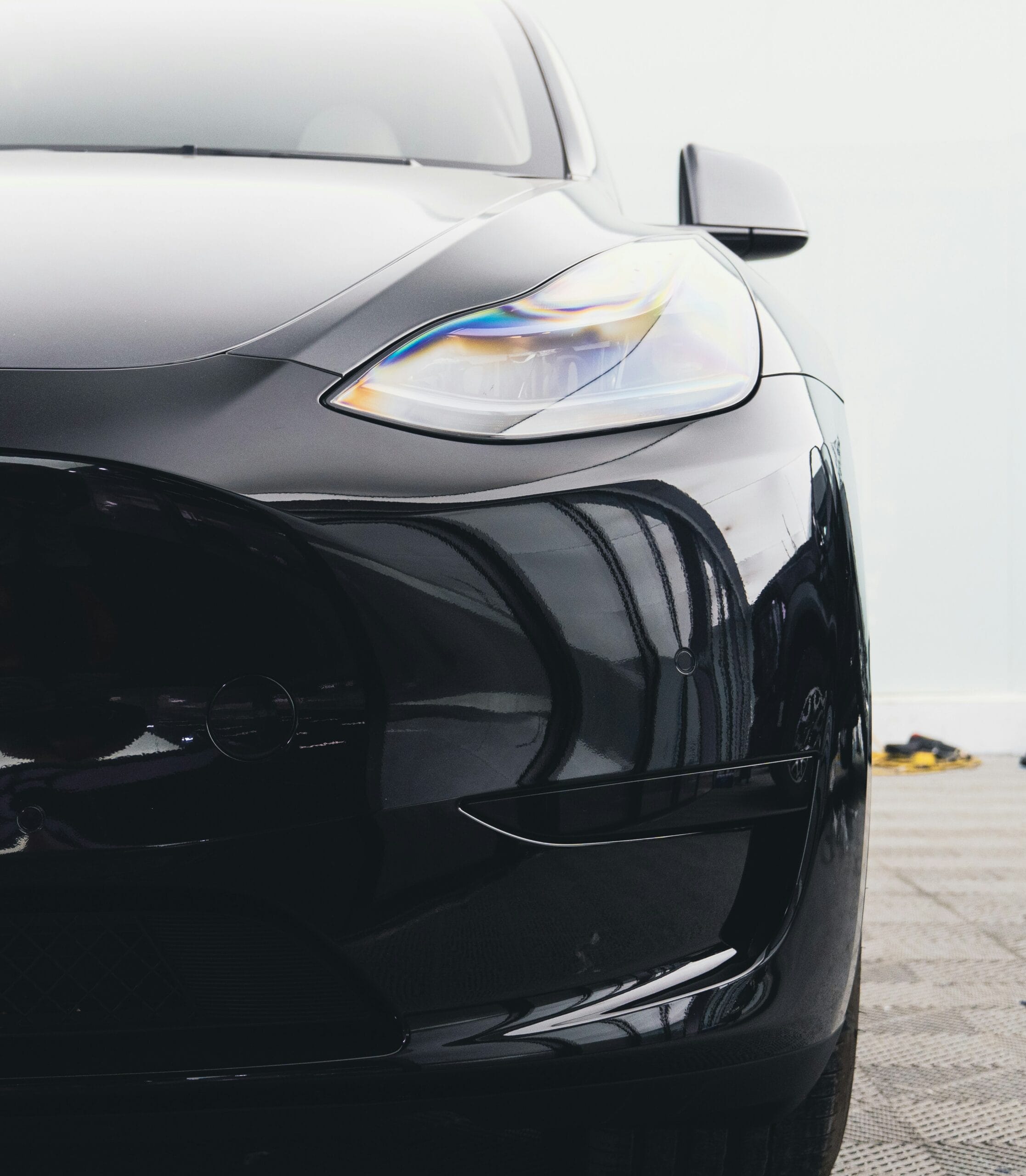 Nærbillede af en sort Tesla, der viser frontens moderne design og forlygte.