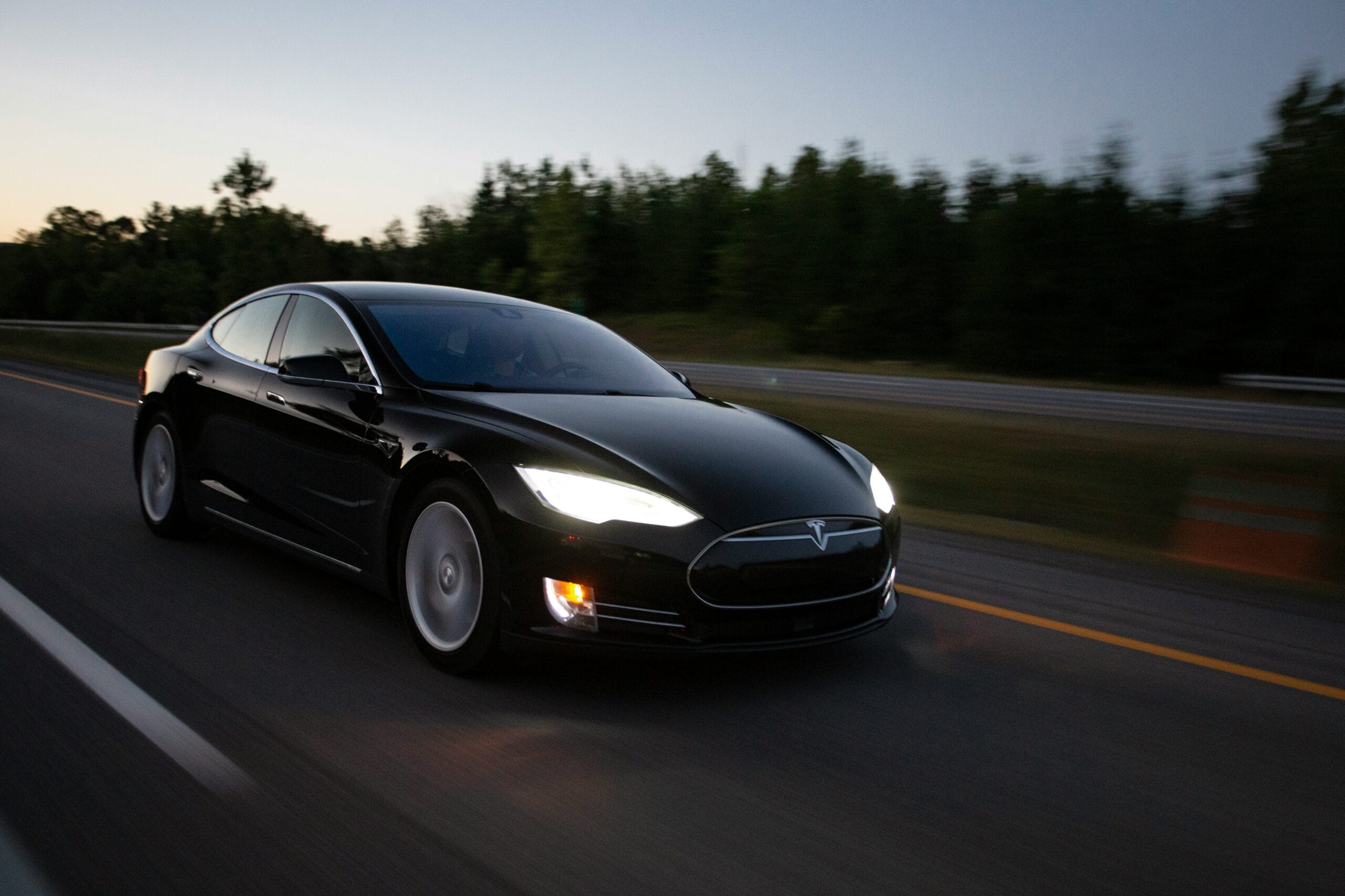 Sort Tesla Model S kører på motorvej i skumringen