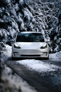 Tesla Model 3 kører gennem snedækket skovvej om vinteren