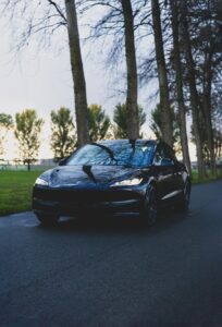 Sort Tesla kører gennem en skovvej om aftenen
