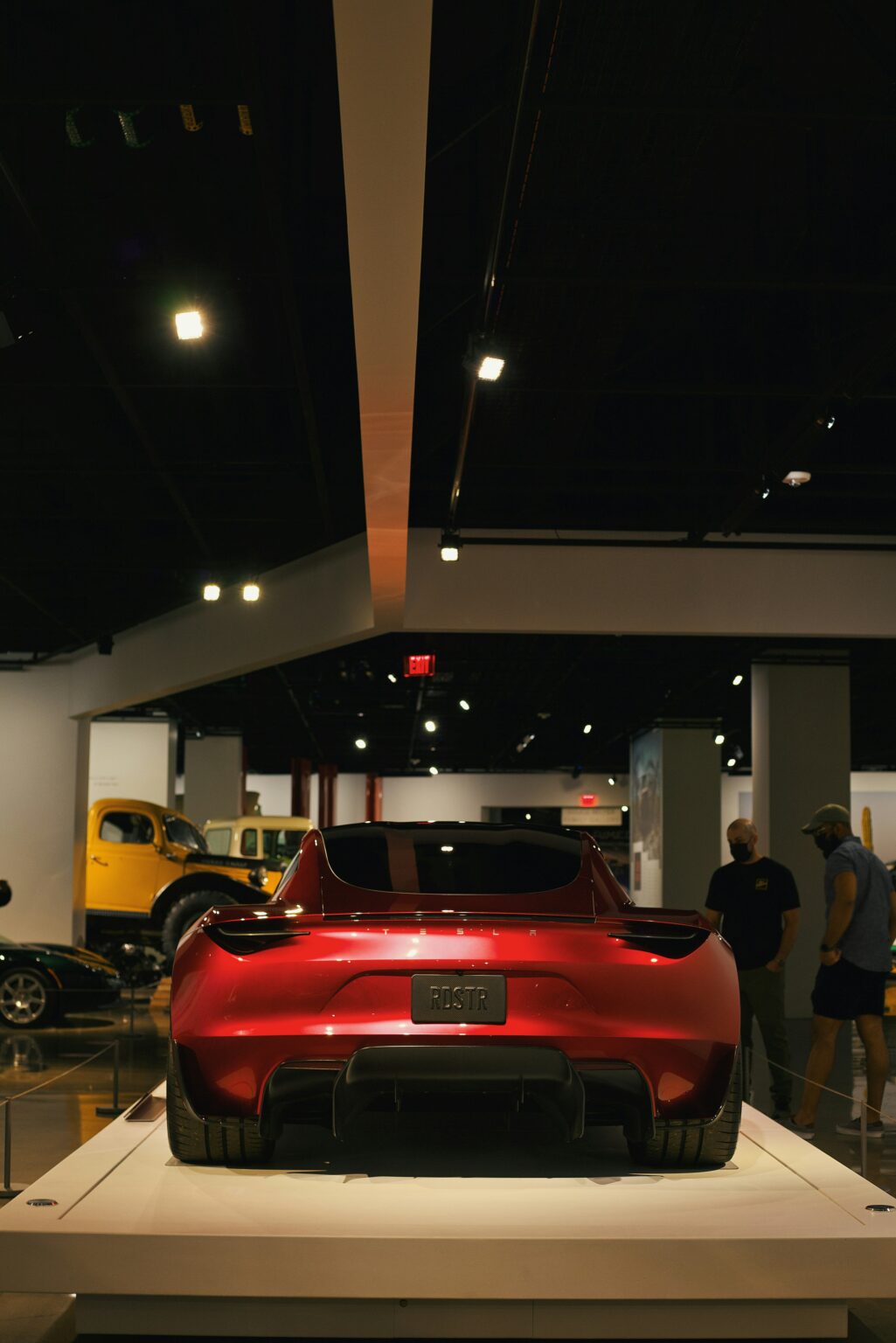 Rød Tesla Roadster udstillet i museum med folk i baggrunden