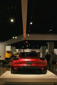 Rød Tesla Roadster udstillet i museum med folk i baggrunden