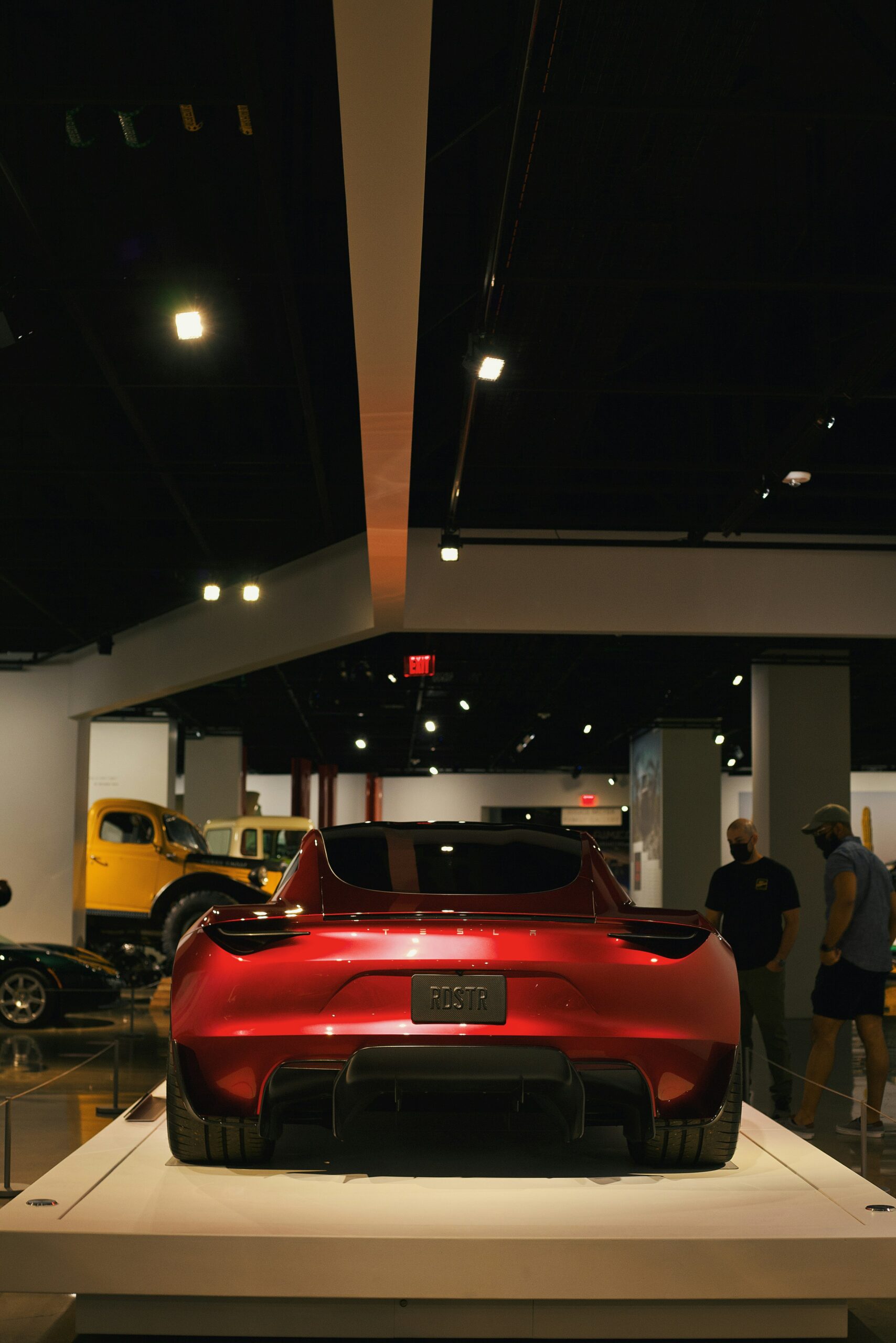 Rød Tesla Roadster udstillet i museum med folk i baggrunden