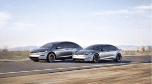 To Tesla-biler kører på en landevej i et ørkenlandskab
