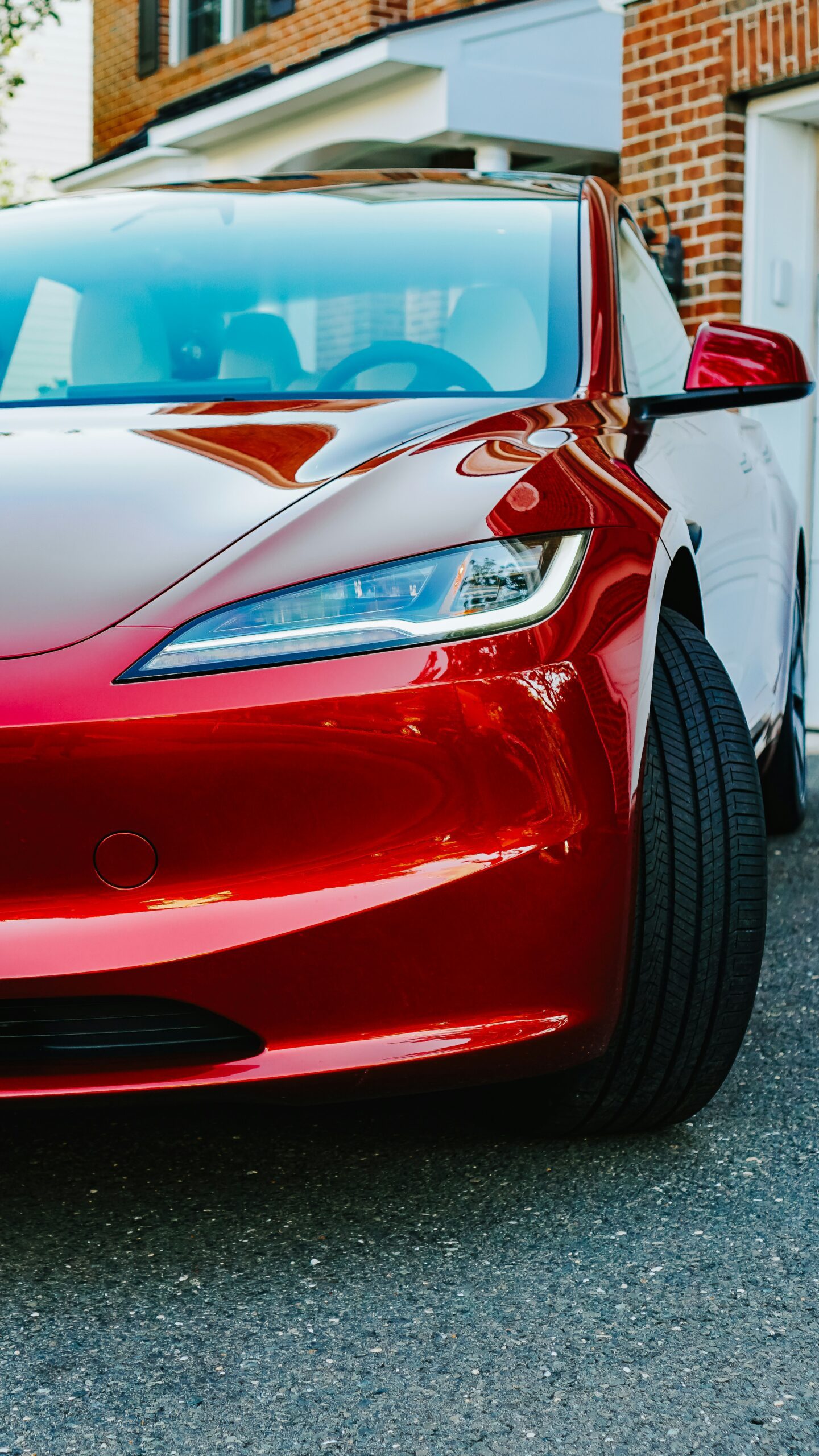 Nærbillede af en rød Tesla parkeret foran et hus