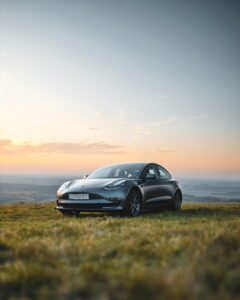 Tesla Model 3 i solnedgang på en bakketop