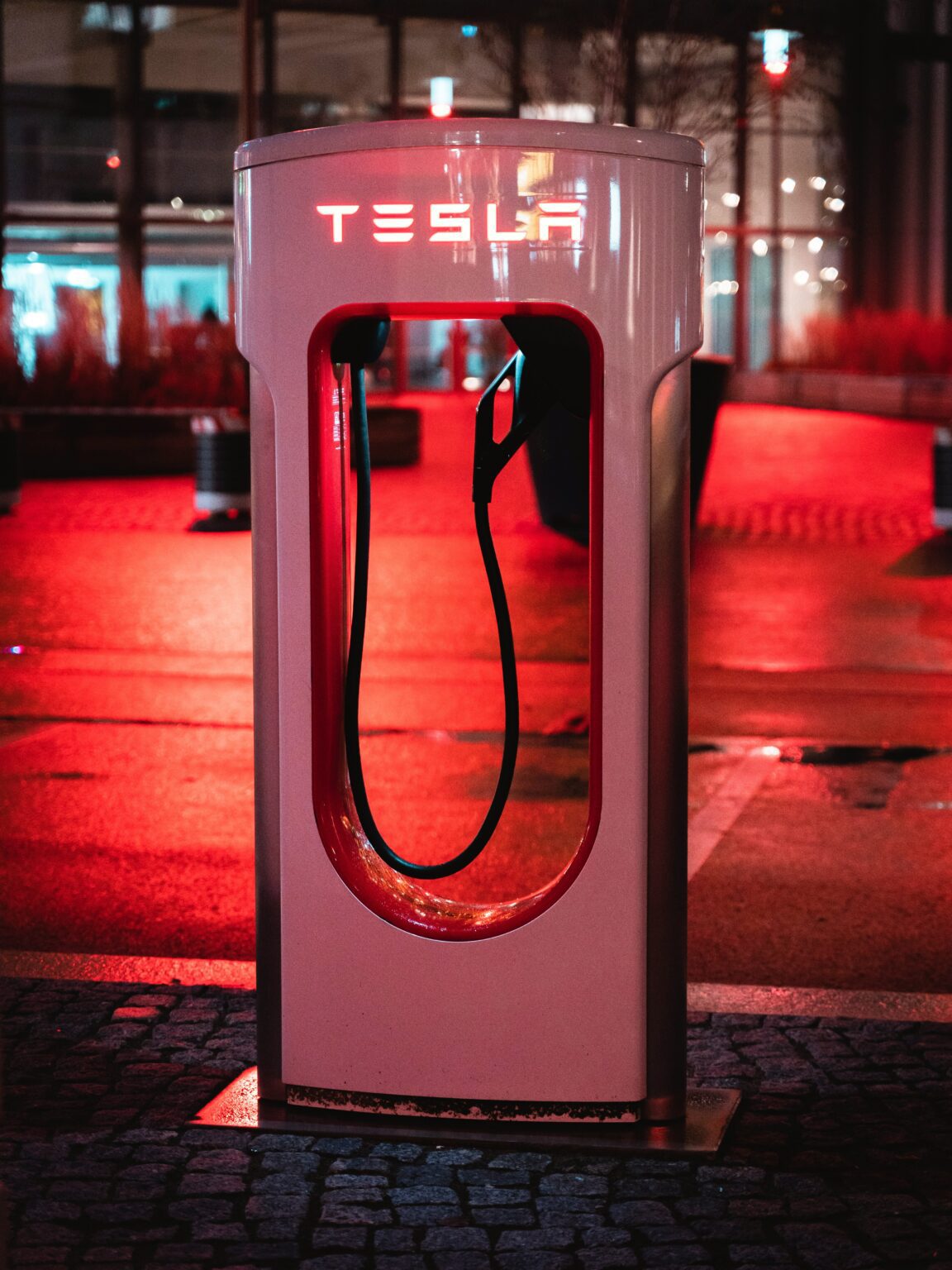 Tesla-ladestation oplyst i rød neon om natten