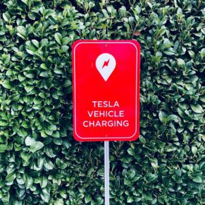 Tesla ladestation skilt mod grøn baggrund