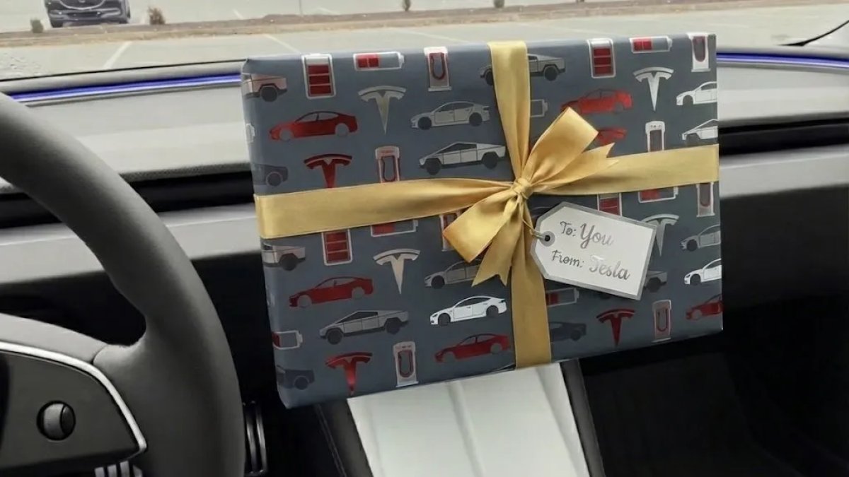 Gave indpakket i Tesla-tema med bånd og kort inde i en Tesla-bil.