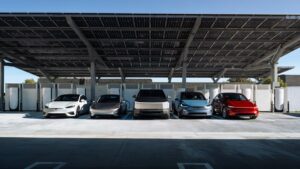 Fem Tesla-biler oplader under en overdækning med solpaneler
