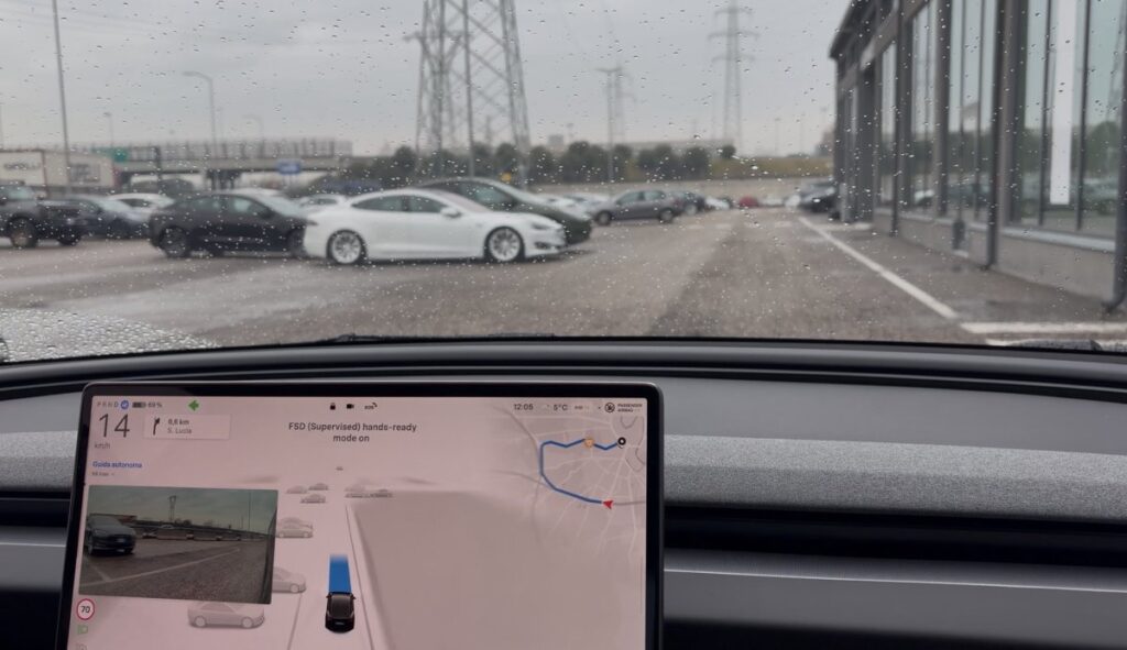 Tesla med regnvåde ruder og skærm, der viser selvkørende funktionalitet