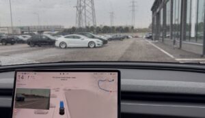 Tesla med regnvåde ruder og skærm, der viser selvkørende funktionalitet
