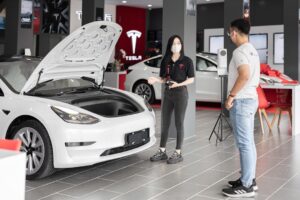 To personer ser på en Tesla i en biludstilling med åbent frunk-låg