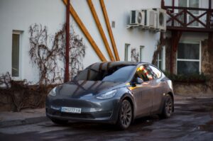 Tesla Model Y parkeret foran en bygning med klatreplanter og aircondition enheder på væggen