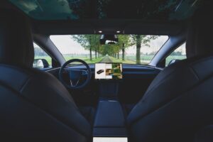 Interiør af en Tesla, der viser avanceret teknologi og minimalistisk design på en naturskøn vej