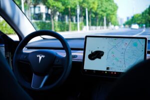 Tesla bilinteriør med touchskærm, der viser navigationskort og autopilot funktioner