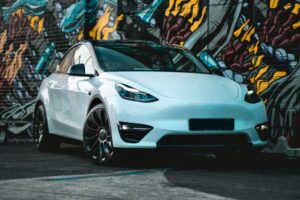 Hvid Tesla parkeret foran en farverig graffitivæg