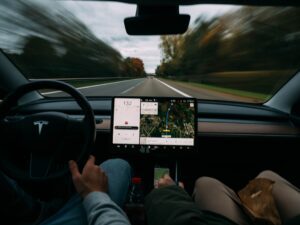Visning fra førersædet af en Tesla, der kører på en motorvej med touchskærm-teknologi i brug.