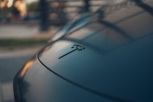 Nærbillede af Tesla-logo på bilens front, skinnende i sollys