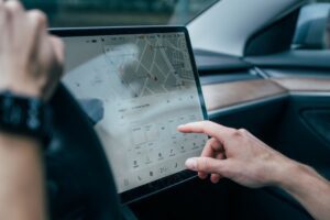 Person interagerer med Tesla-bilens touchscreen med navigation og indstillinger