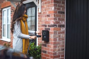 Kvinde oplader elektrisk bil ved ladestation hjemme
